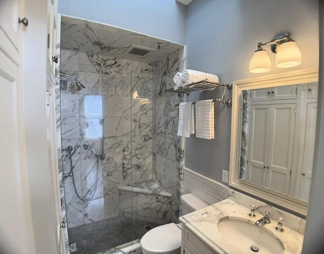 full bathroom featuring toilet, a marble finish shower, and vanity