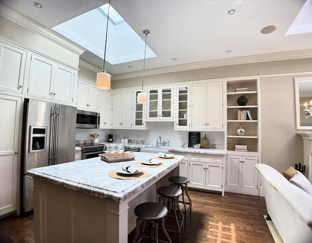kitchen featuring appliances with stainless steel finishes, a skylight, ornamental molding, dark wood-style flooring, and white cabinetry