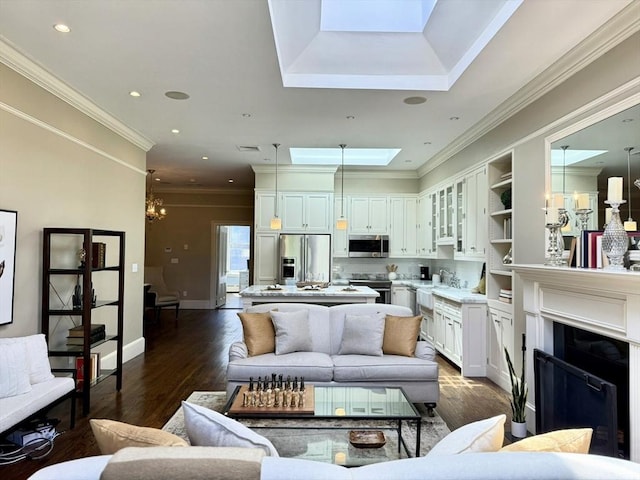 living room with a skylight, dark wood-type flooring, a chandelier, ornamental molding, and baseboards