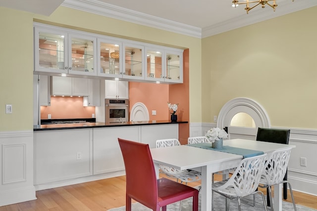 dining area with ornamental molding, light hardwood / wood-style flooring, and a notable chandelier