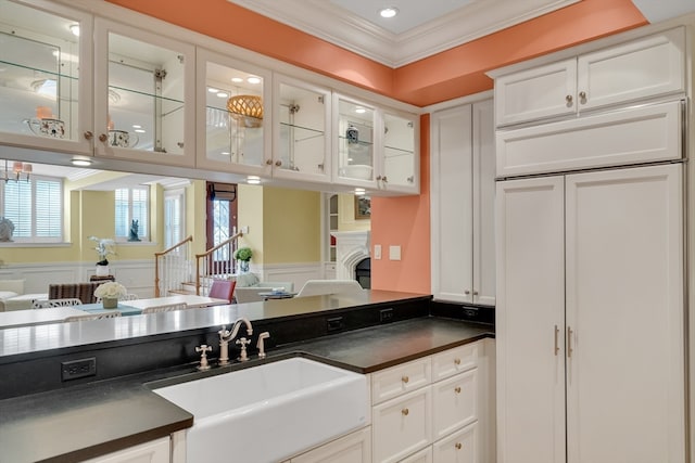 kitchen with a healthy amount of sunlight, sink, crown molding, and white cabinetry