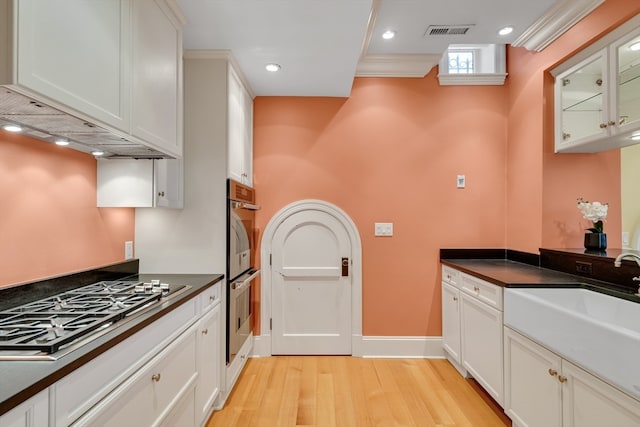 kitchen with white cabinets, crown molding, light hardwood / wood-style flooring, stainless steel appliances, and sink