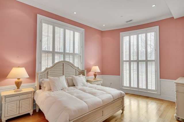 bedroom featuring light hardwood / wood-style flooring, crown molding, and multiple windows