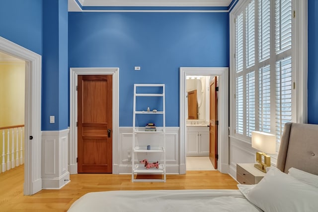 bedroom with light hardwood / wood-style flooring, ensuite bathroom, and multiple windows