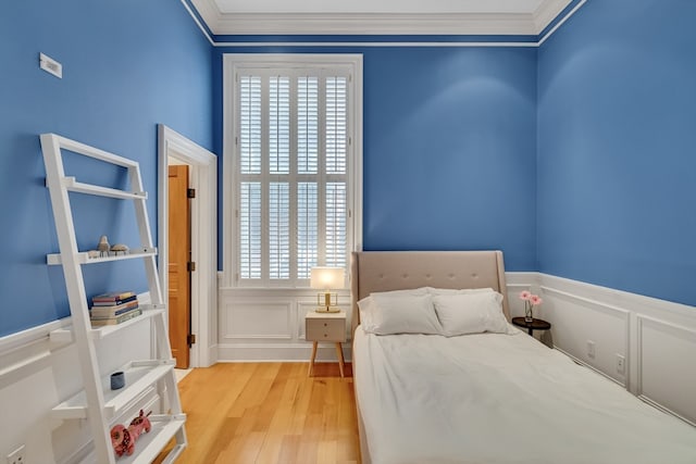 bedroom with light hardwood / wood-style flooring, crown molding, and multiple windows