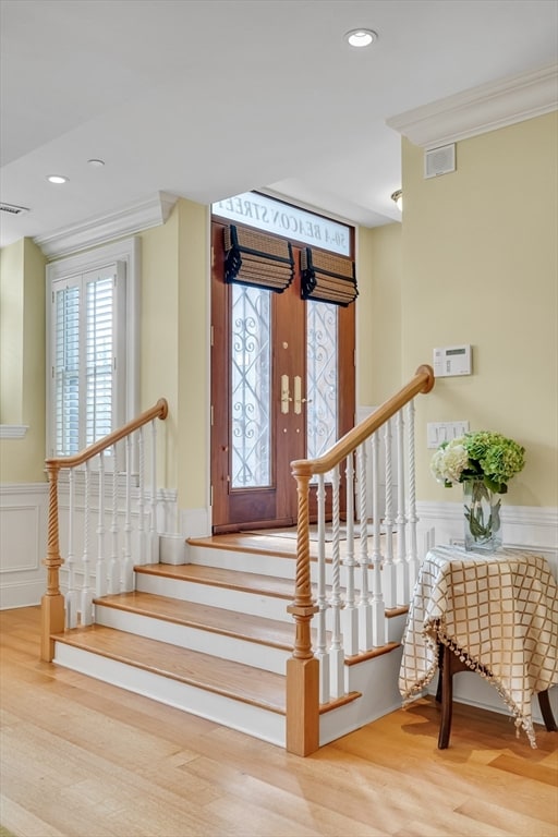 stairway with crown molding and light hardwood / wood-style flooring