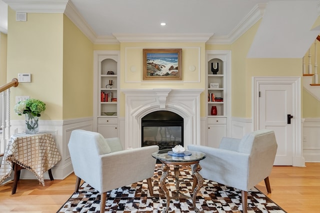 living room with built in features, crown molding, and light wood-type flooring