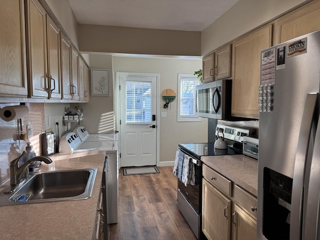 kitchen featuring washing machine and dryer, dark wood-type flooring, stainless steel appliances, light brown cabinetry, and sink