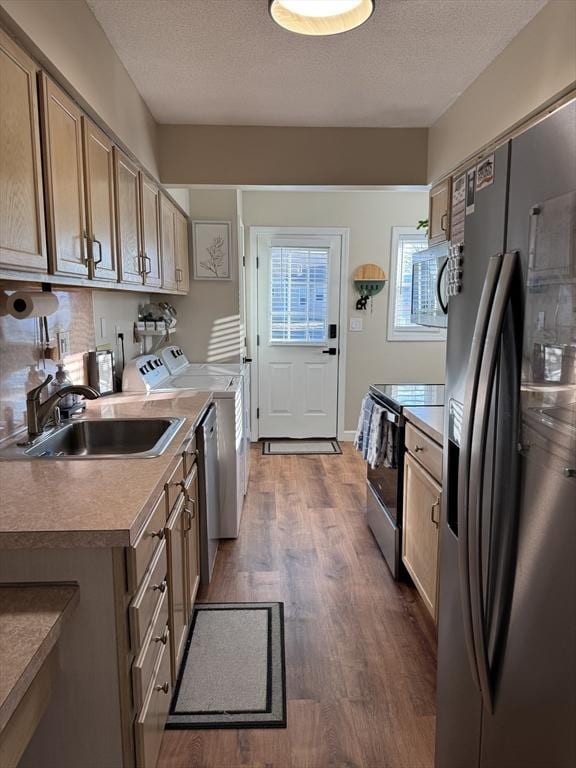 kitchen featuring independent washer and dryer, sink, stainless steel appliances, a textured ceiling, and dark hardwood / wood-style flooring