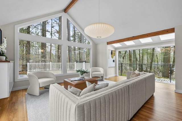 living room with a wealth of natural light, wood finished floors, beam ceiling, and a skylight