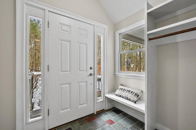 entryway featuring a wealth of natural light, baseboards, lofted ceiling, and stone finish floor