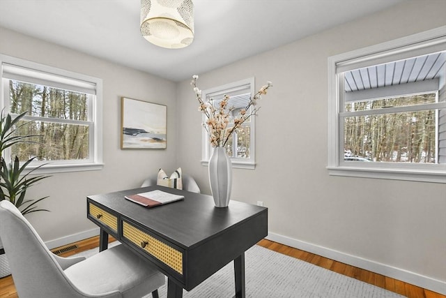 office space featuring wood finished floors, visible vents, and baseboards