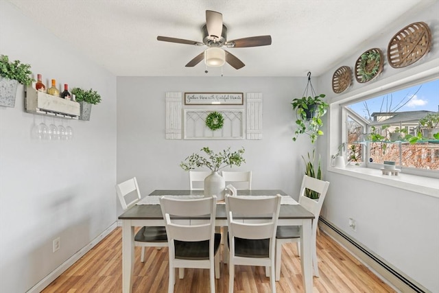 dining area with light wood finished floors, baseboard heating, baseboards, and a ceiling fan