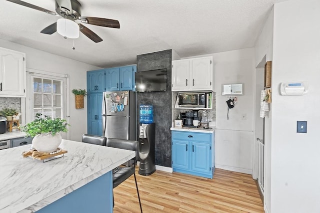 kitchen with white cabinetry, light countertops, blue cabinetry, and light wood-type flooring