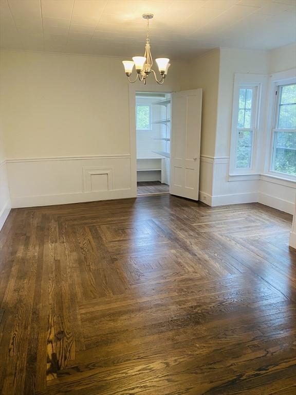 unfurnished room featuring dark parquet floors and an inviting chandelier