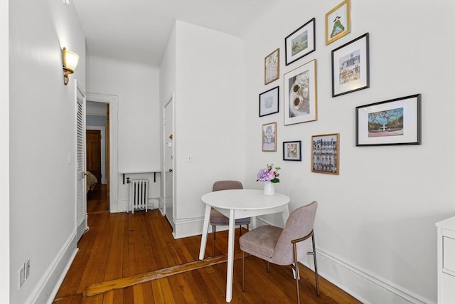 dining room with radiator heating unit, baseboards, and wood-type flooring