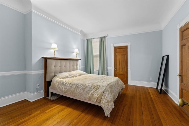 bedroom with wood-type flooring, crown molding, and baseboards