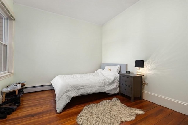 bedroom with baseboards, baseboard heating, and wood finished floors