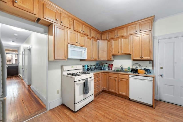 kitchen featuring light wood-style floors, white appliances, a sink, and baseboards