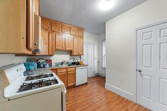 kitchen featuring white appliances, baseboards, light wood-style flooring, light countertops, and a sink