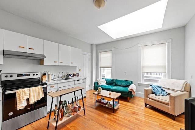 kitchen featuring a skylight, dishwasher, stainless steel electric range oven, under cabinet range hood, and a sink