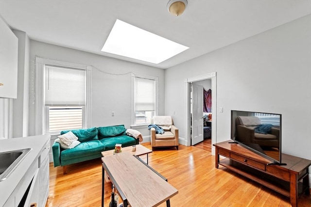 living area featuring a skylight and light wood-style flooring