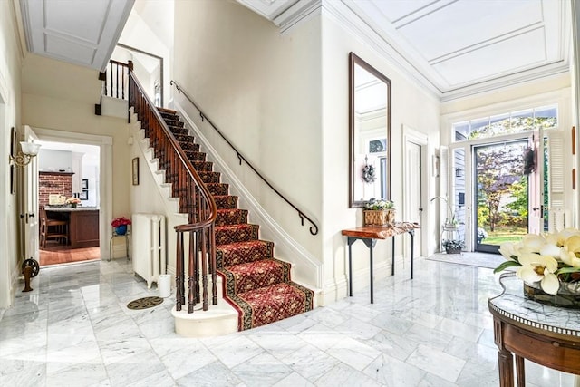 foyer with marble finish floor, crown molding, a high ceiling, baseboards, and stairs