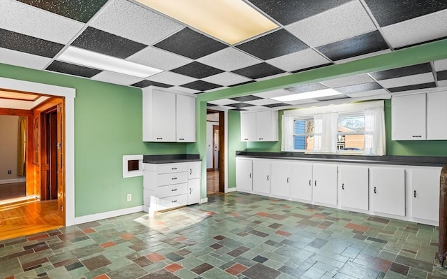 kitchen featuring a paneled ceiling and white cabinetry