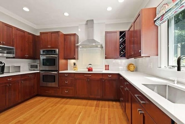 51 Fox Run Rd, Sudbury, MA 01776 - kitchen with wall chimney exhaust hood, appliances with stainless steel finishes, ornamental molding, light countertops, and light wood finished floors