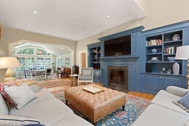 51 Fox Run Rd, Sudbury, MA 01776 - living room featuring light wood finished floors, a fireplace with flush hearth, vaulted ceiling, recessed lighting, and arched walkways