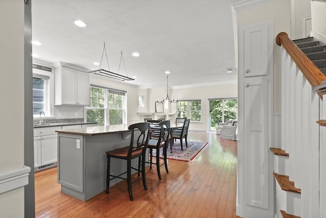 21 Pine St Unit 1A, Falmouth, MA 02556 - kitchen with healthy amount of natural light, a breakfast bar, light wood-style floors, ornamental molding, and dark stone countertops