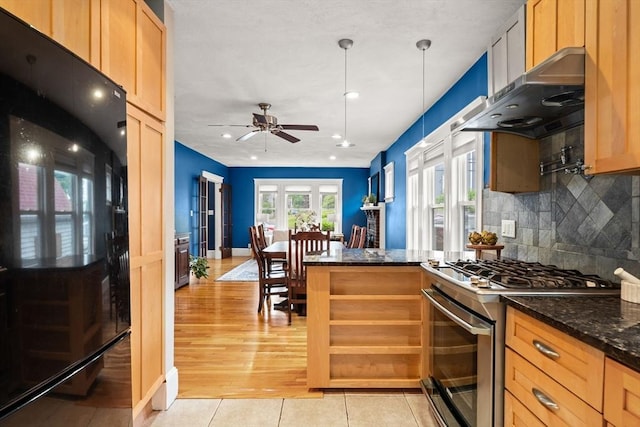 338 Forest St, Arlington, MA 02474 - kitchen with stainless steel range with gas cooktop, refrigerator, wall chimney range hood, a ceiling fan, and tasteful backsplash