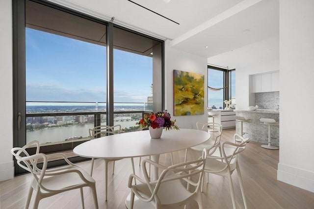 dining room with a water view, expansive windows, and light wood-type flooring