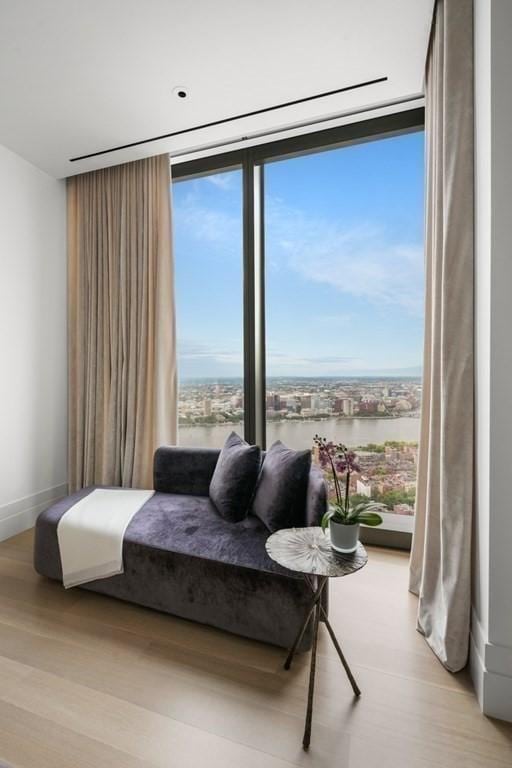 bedroom with floor to ceiling windows, a water view, baseboards, and wood finished floors