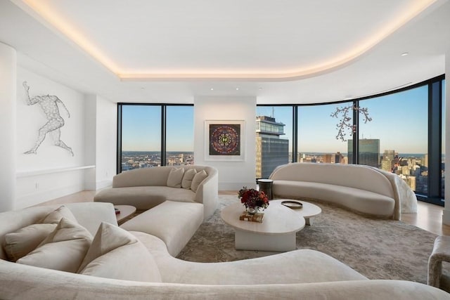 living area featuring a city view, floor to ceiling windows, wood finished floors, and a raised ceiling