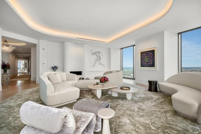 living room featuring floor to ceiling windows, a tray ceiling, and wood finished floors