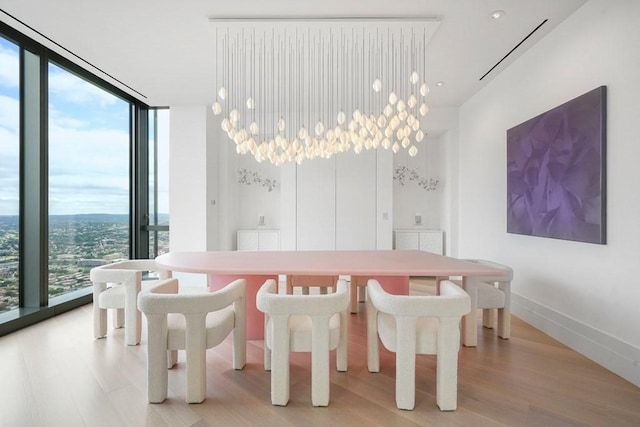 dining space with expansive windows, light wood-style floors, and baseboards