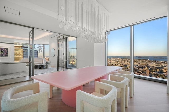 dining space with floor to ceiling windows, a water view, hardwood / wood-style floors, and a wealth of natural light