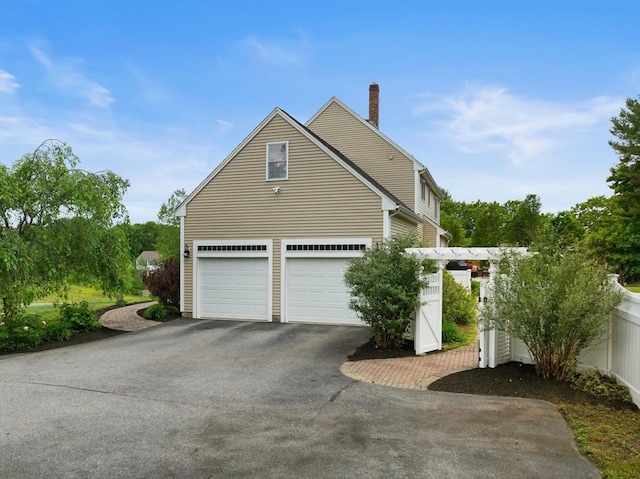 55 Arbor Rd, Uxbridge, MA 01569 - view of home's exterior featuring asphalt driveway, a chimney, and a garage