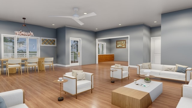 living room featuring ceiling fan with notable chandelier and light wood-type flooring