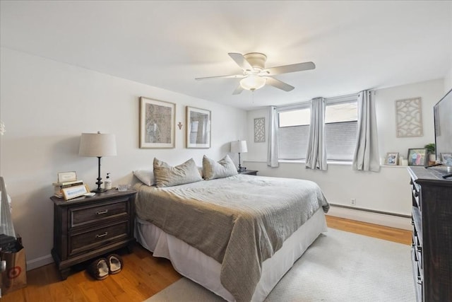 bedroom with light wood-style flooring, a ceiling fan, baseboards, and a baseboard radiator