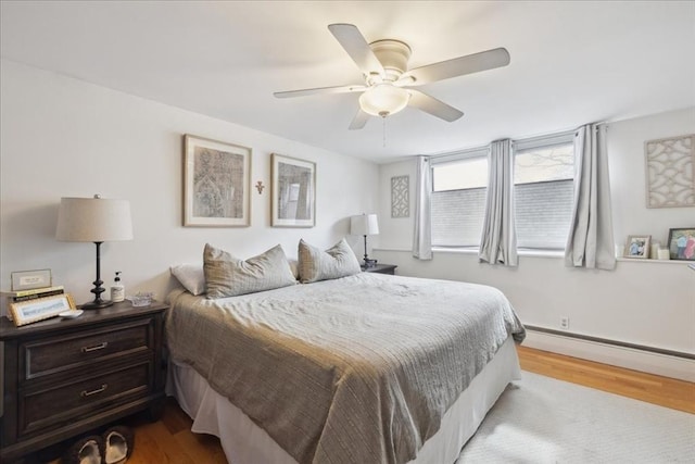 bedroom with wood finished floors, a ceiling fan, and a baseboard radiator