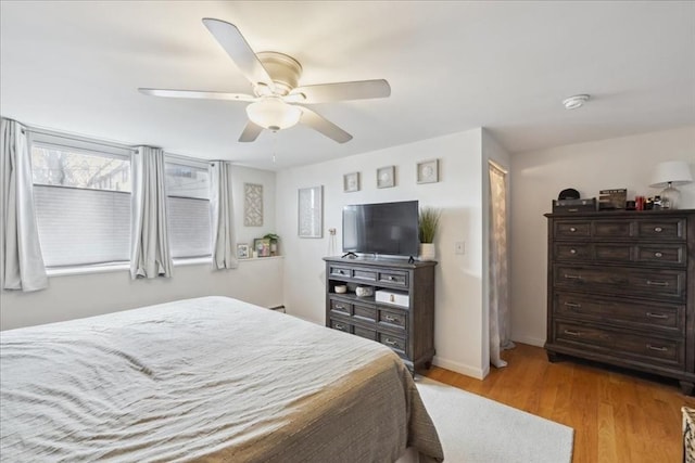 bedroom with light wood-style floors, baseboards, and ceiling fan