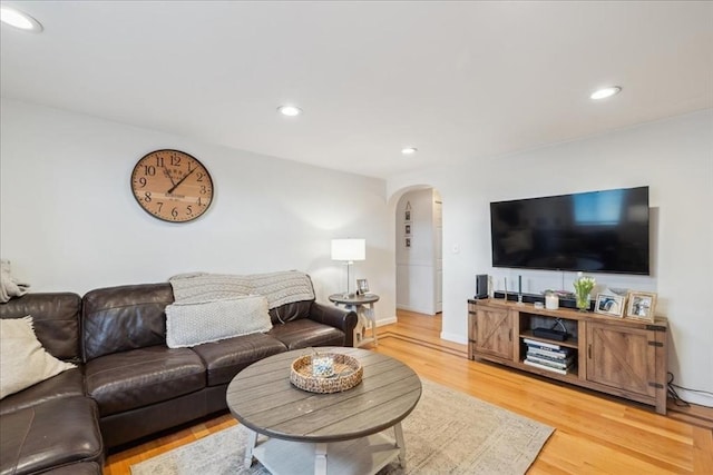 living room with recessed lighting, arched walkways, light wood finished floors, and baseboards