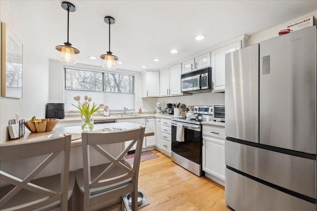 kitchen featuring light wood-style floors, appliances with stainless steel finishes, white cabinets, and light countertops