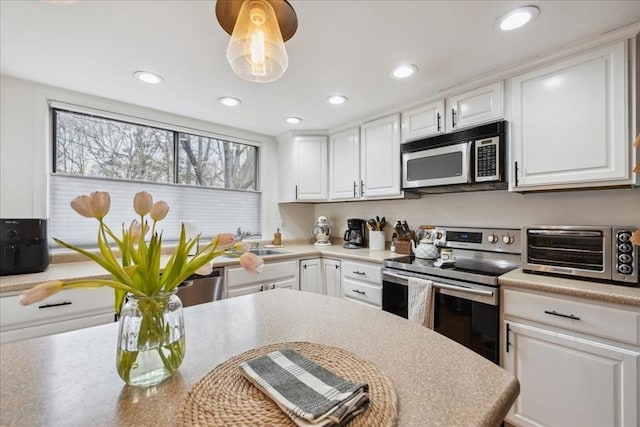 kitchen featuring white cabinetry, a toaster, a sink, and stainless steel appliances