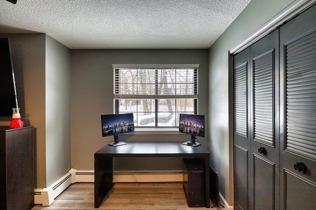 office area with a baseboard heating unit, a textured ceiling, and wood finished floors