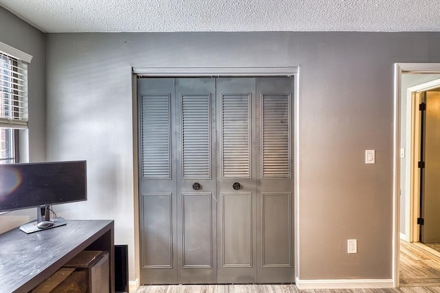 home office featuring a textured ceiling, wood finished floors, and baseboards