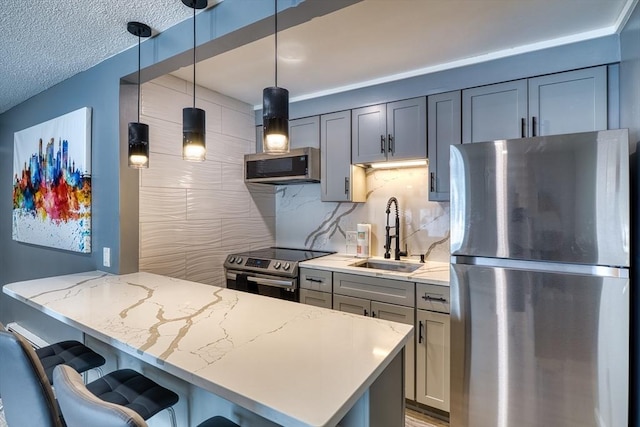 kitchen featuring a breakfast bar, backsplash, appliances with stainless steel finishes, a sink, and light stone countertops