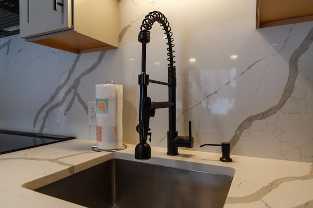 details featuring a sink and light stone countertops